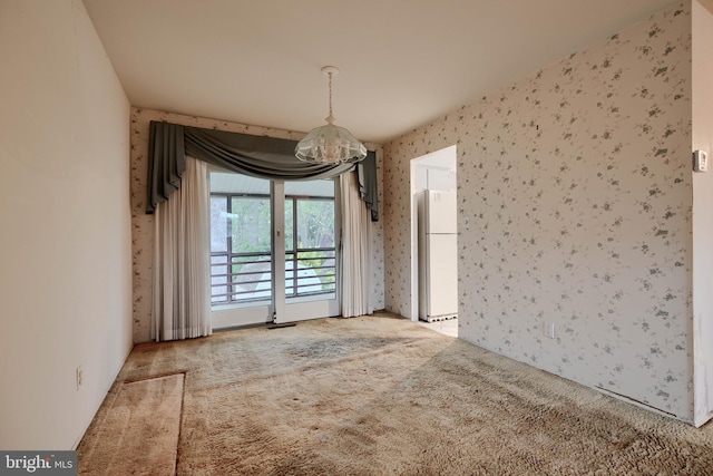 unfurnished dining area with carpet floors, a notable chandelier, and wallpapered walls