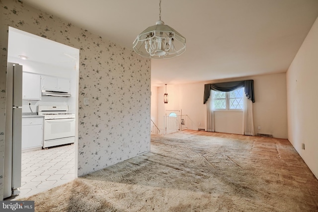 unfurnished living room with visible vents, a chandelier, and wallpapered walls