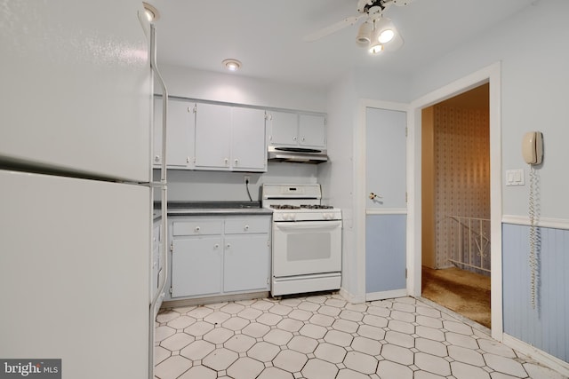kitchen with under cabinet range hood, light floors, dark countertops, a ceiling fan, and white appliances