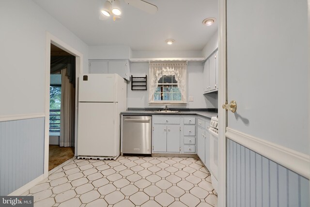 kitchen with a wealth of natural light, a wainscoted wall, a sink, and white appliances
