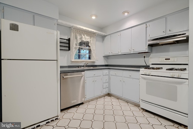 kitchen featuring dark countertops, a sink, white appliances, light floors, and under cabinet range hood