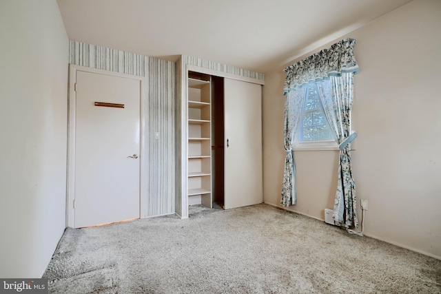 unfurnished bedroom with baseboards, carpet floors, wallpapered walls, and a closet