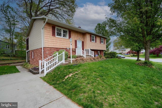 split foyer home with a front lawn and brick siding