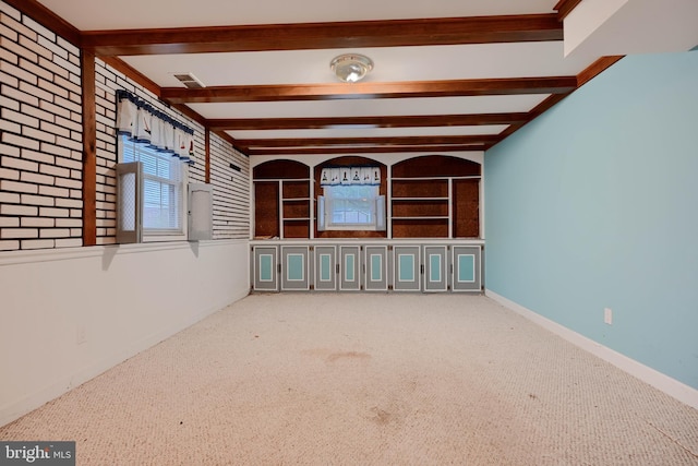 spare room with beamed ceiling, carpet floors, a wealth of natural light, and visible vents