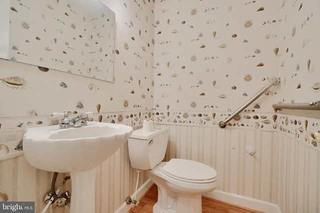 bathroom with toilet, a wainscoted wall, wood finished floors, and wallpapered walls
