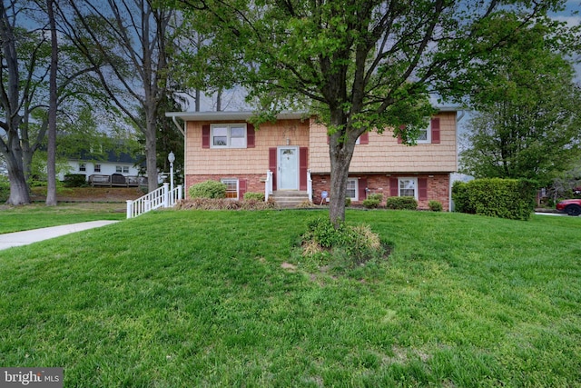 bi-level home with a front lawn, entry steps, and brick siding