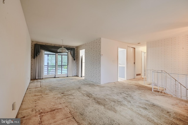 unfurnished room featuring wallpapered walls and carpet