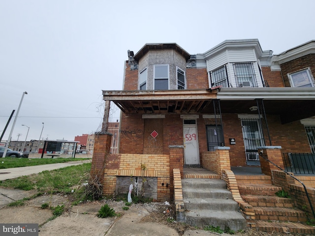 townhome / multi-family property featuring brick siding and covered porch
