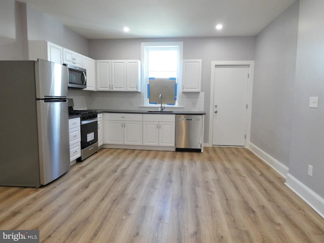 2147 W Grange Ave, Philadelphia, PA 19138 - kitchen with baseboards, a sink, appliances with stainless steel finishes, white cabinetry, and backsplash