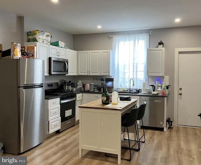2147 W Grange Ave, Philadelphia, PA 19138 - kitchen featuring light wood-type flooring, a center island, white cabinetry, stainless steel appliances, and a sink
