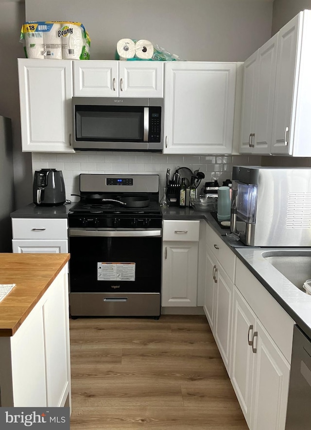 2147 W Grange Ave, Philadelphia, PA 19138 - kitchen with wood counters, white cabinetry, decorative backsplash, stainless steel appliances, and light wood finished floors