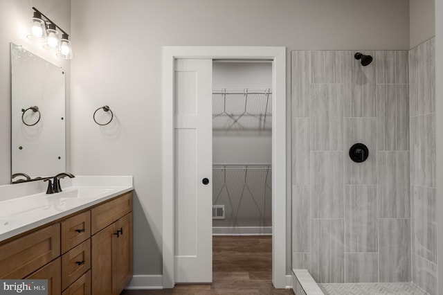309 Gun Club Rd, Stephenson, VA 22656 - full bathroom featuring a tile shower, vanity, visible vents, wood finished floors, and a walk in closet