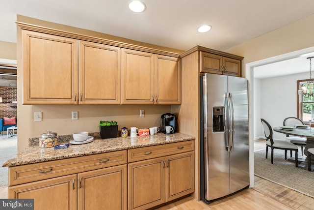 kitchen featuring an inviting chandelier, stainless steel fridge with ice dispenser, light wood-type flooring, light stone counters, and recessed lighting