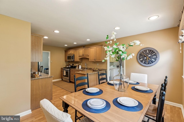 dining area with light wood finished floors, washing machine and clothes dryer, and baseboards