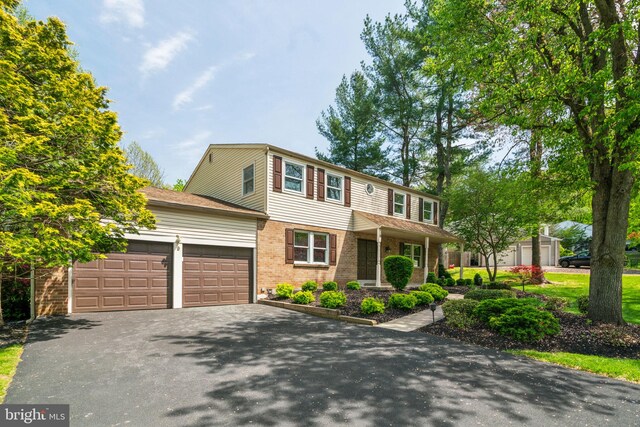 view of front facade with driveway, brick siding, and an attached garage