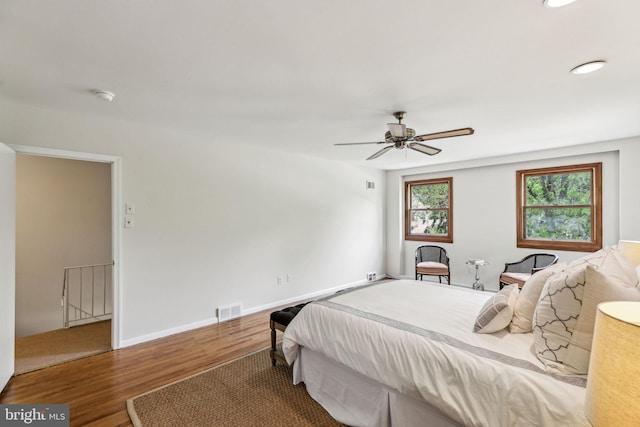 bedroom with baseboards, ceiling fan, visible vents, and wood finished floors