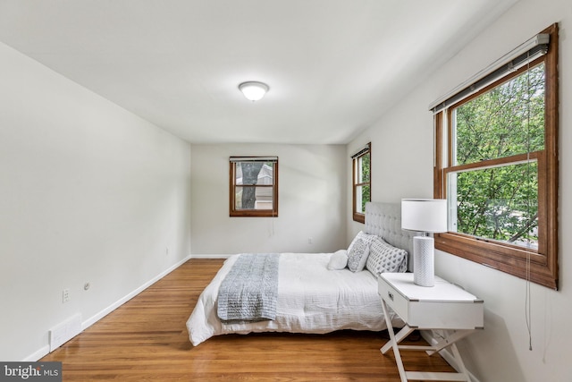 bedroom featuring baseboards, visible vents, and wood finished floors
