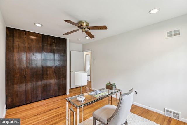 home office featuring light wood-style flooring, baseboards, a ceiling fan, and visible vents