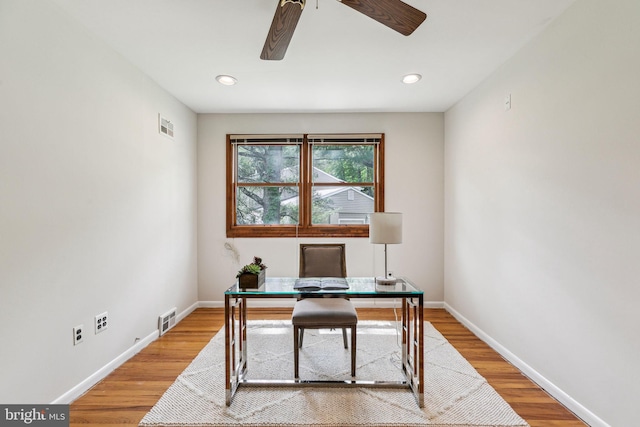 office space with visible vents, wood finished floors, baseboards, and ceiling fan