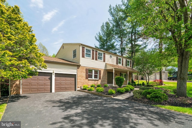 view of front of property with an attached garage, brick siding, and aphalt driveway