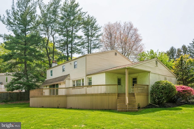 rear view of house with a yard, stairs, a chimney, and fence