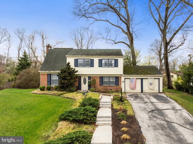 colonial house featuring a chimney, driveway, a front yard, and brick siding