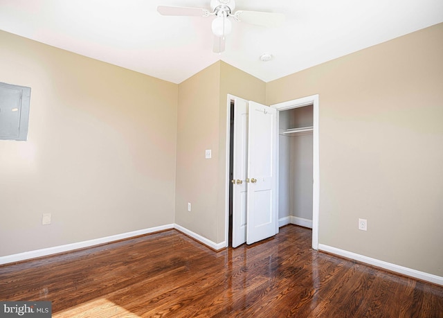 unfurnished bedroom with a closet, a ceiling fan, electric panel, wood finished floors, and baseboards