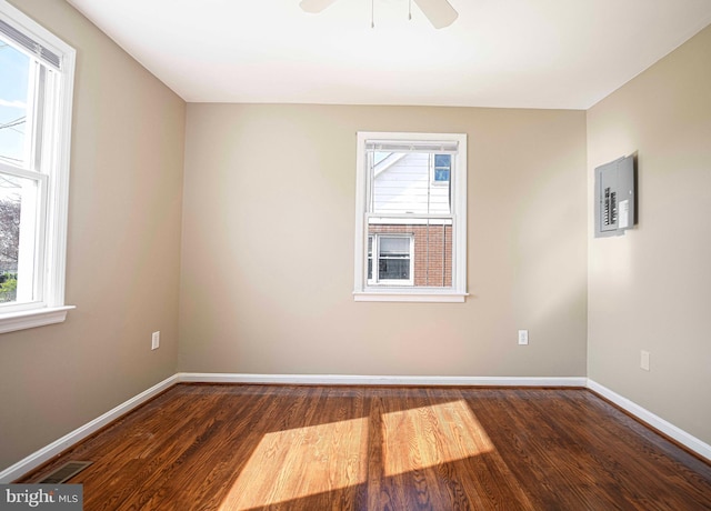 empty room with wood finished floors, ceiling fan, baseboards, and visible vents