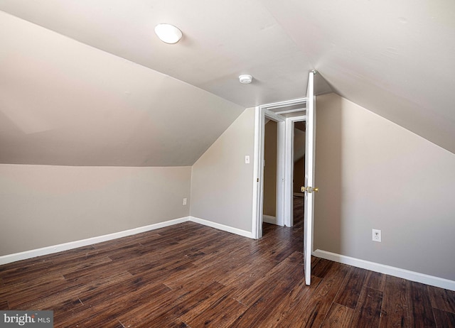 additional living space featuring baseboards, vaulted ceiling, and dark wood-style floors