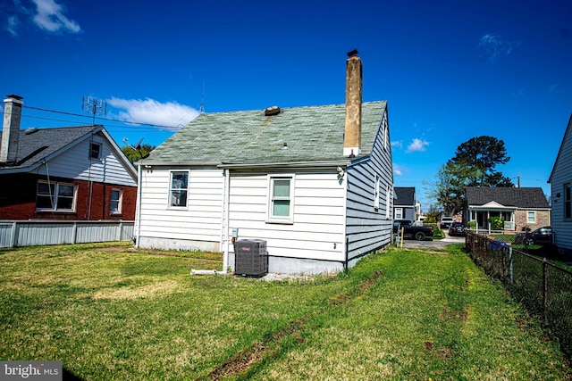 back of house featuring a yard, fence, central AC unit, and a chimney