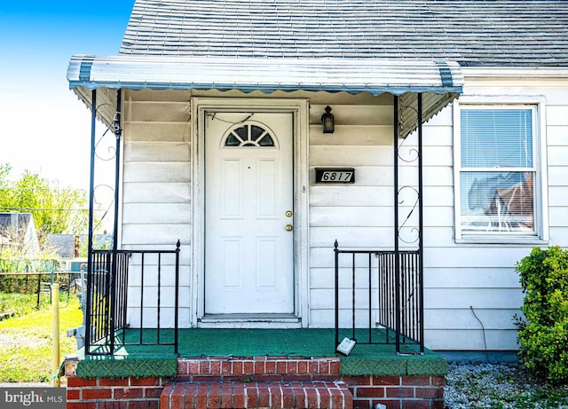 doorway to property with roof with shingles