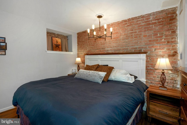 bedroom with brick wall, a notable chandelier, and wood finished floors
