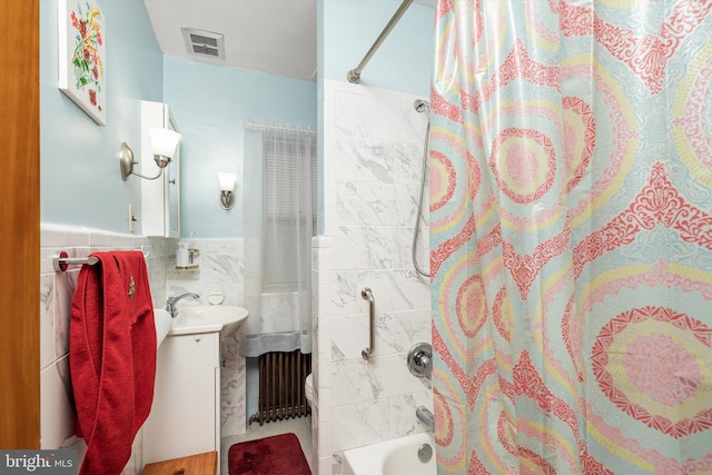 full bathroom featuring vanity, shower / tub combo with curtain, visible vents, wainscoting, and tile walls