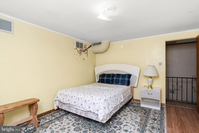 bedroom with wood finished floors, baseboards, and visible vents