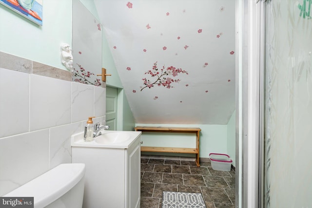 bathroom featuring stone finish flooring, vanity, tile walls, and toilet