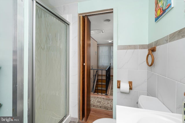 bathroom with a shower stall, toilet, vanity, and tile walls