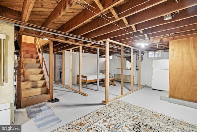 below grade area with stairs and freestanding refrigerator