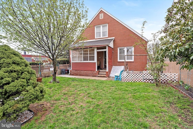 rear view of house with a sunroom, entry steps, a yard, and fence