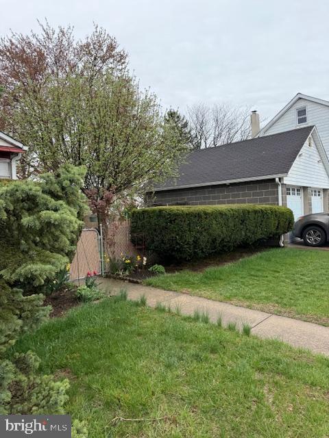 view of home's exterior with an attached garage, a lawn, and a chimney