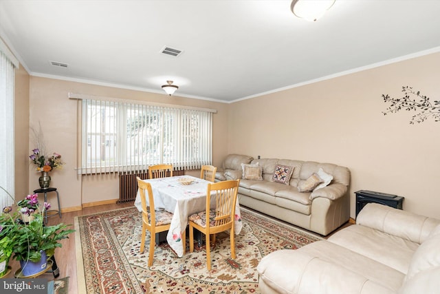 living room with crown molding, visible vents, baseboards, and wood finished floors