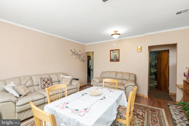 living area with ornamental molding, visible vents, baseboards, and wood finished floors