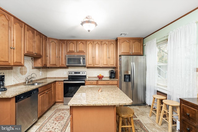 kitchen with visible vents, a center island, a sink, appliances with stainless steel finishes, and light stone countertops