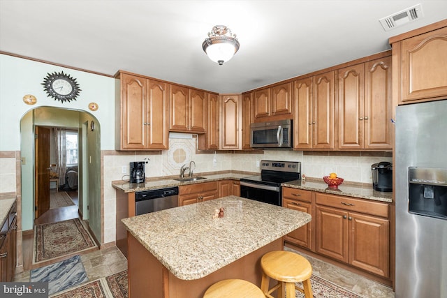 kitchen with a kitchen breakfast bar, visible vents, stainless steel appliances, arched walkways, and a sink