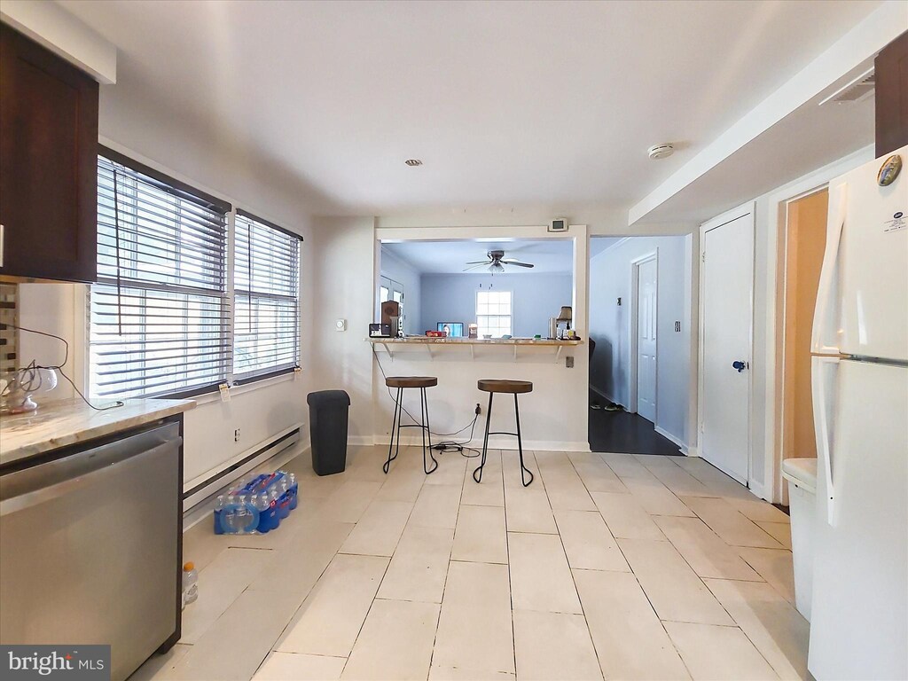 3115 New Coach Ln, Bowie, MD 20716 - kitchen with a baseboard heating unit, freestanding refrigerator, a ceiling fan, a kitchen bar, and dishwasher