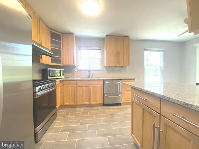 97 Kirkwood Dr, Newtown, PA 18940 - kitchen with light stone counters, decorative backsplash, glass insert cabinets, stainless steel appliances, and under cabinet range hood