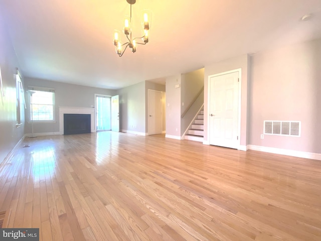 97 Kirkwood Dr, Newtown, PA 18940 - unfurnished living room featuring an inviting chandelier, visible vents, baseboards, light wood-style flooring, and stairs