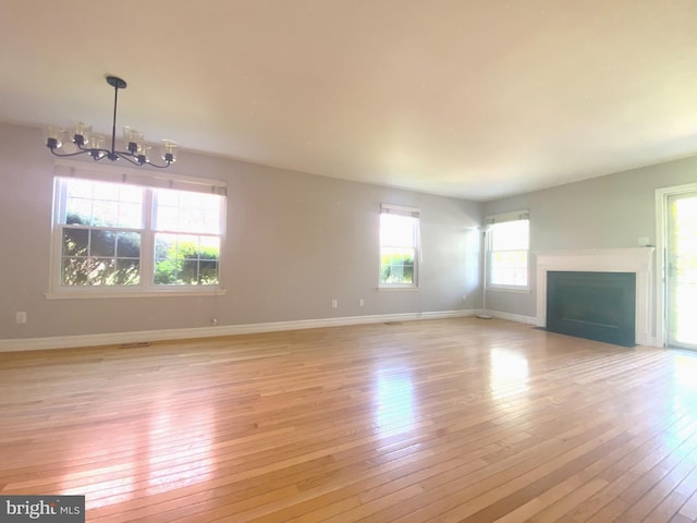 97 Kirkwood Dr, Newtown, PA 18940 - unfurnished living room featuring light wood-type flooring, baseboards, a chandelier, and a fireplace with flush hearth