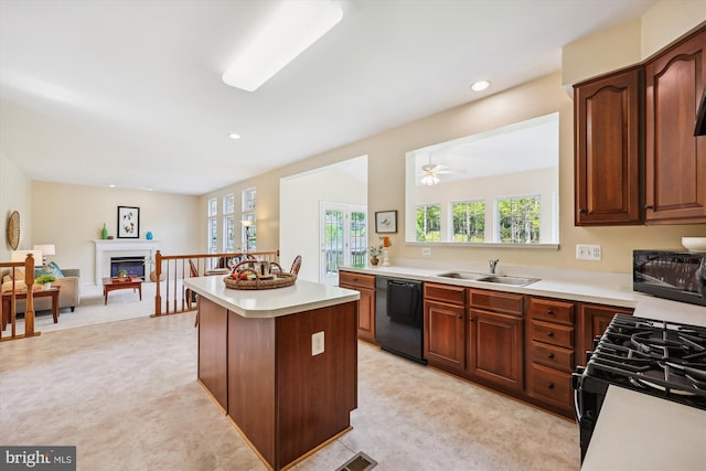 kitchen with a healthy amount of sunlight, a sink, light countertops, black appliances, and light floors