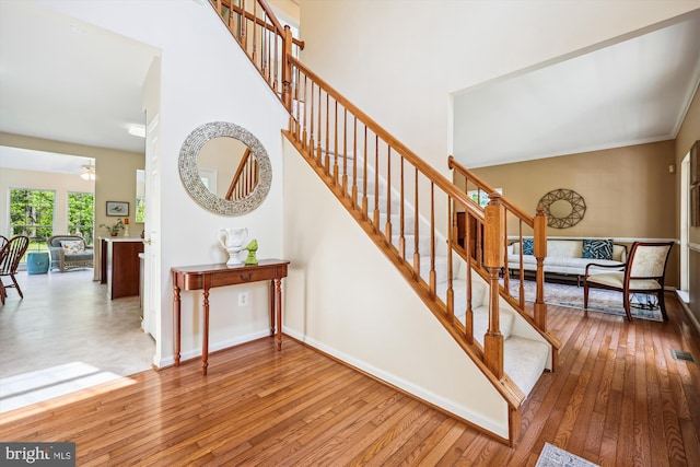 staircase with baseboards, a high ceiling, and hardwood / wood-style flooring