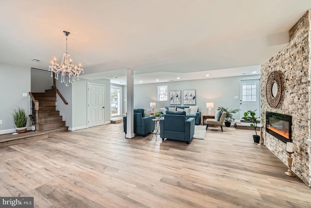 living room featuring light wood-style floors, a fireplace, a wealth of natural light, and stairway